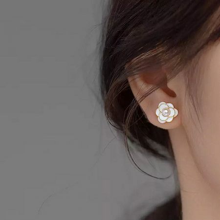 Close-up of the white enamel Camellia flower earring being worn, showcasing its elegant design.