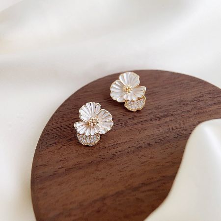 Detailed shot of the 14k gold plated white enamel flower earrings.