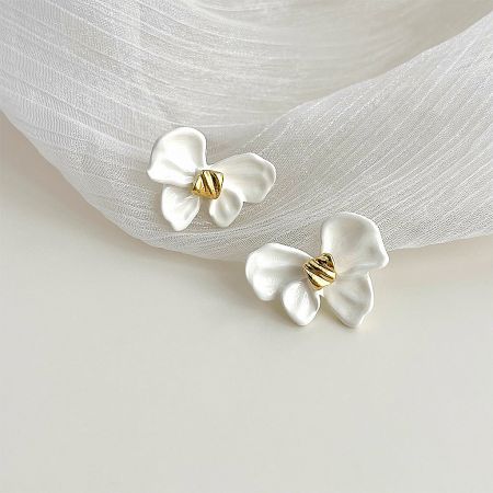 A detailed close-up of the white enamel knot bow earrings, highlighting the intricate gold center and craftsmanship.