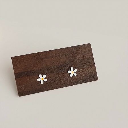 Wholesale Cute Mini Enamel Daisy Flower Stud Earrings (5 Pairs) - A pair of wholesale cute mini enamel daisy flower stud earrings displayed on a rustic wooden block, highlighting their white petals and yellow centers.
