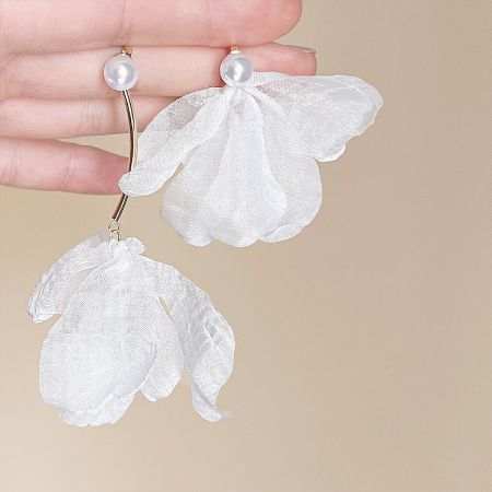 Close-up view of the white floral earrings, emphasizing the combination of pearls and gold details.