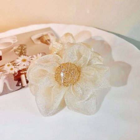 Detailed view of the beige fabric flower scrunchie with a gold glitter center.