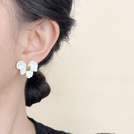 Model wearing the white enamel knot bow stud earring to showcase its size and appearance.