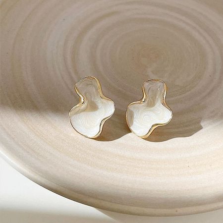 The set of 5 pairs of white enamel and gold earrings artfully arranged on a decorative plate.