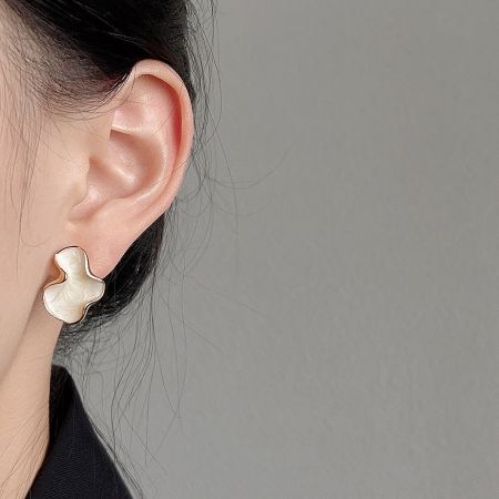 Close-up of a woman wearing the white and gold irregular shape stud earring, showcasing its size and fit.