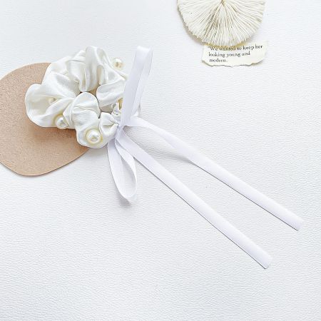 A close-up of the white ribbon pearl hair scrunchie, showcasing its delicate fabric and pearl details.