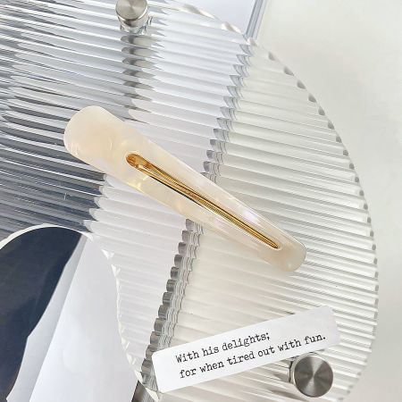 A single white marbled acetate hair clip with a sleek design.