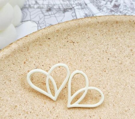 A pair of elegant white heart-shaped enamel earrings, perfect for a romantic summer look.