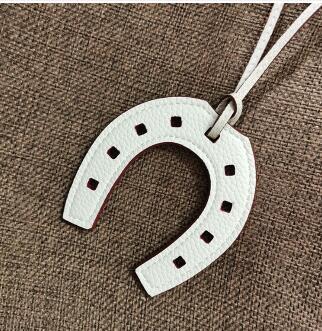 Close-up detail of a white PU leather horseshoe charm showing its texture.