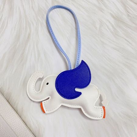 Detailed close-up of the white leather elephant charm, highlighting the stitching and colorful blue and orange wing details.