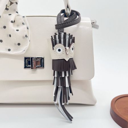 Brown leather owl tassel charm keychain as a fashionable accessory on a purse.