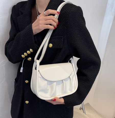 A woman holding the white version of the soft PU leather cross body bag, demonstrating its size and style.