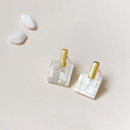 A pair of elegant white mosaic square stud earrings with polished gold posts.