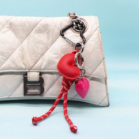 Detailed view of the red star and pink heart PU leather keychain on a white quilted handbag.
