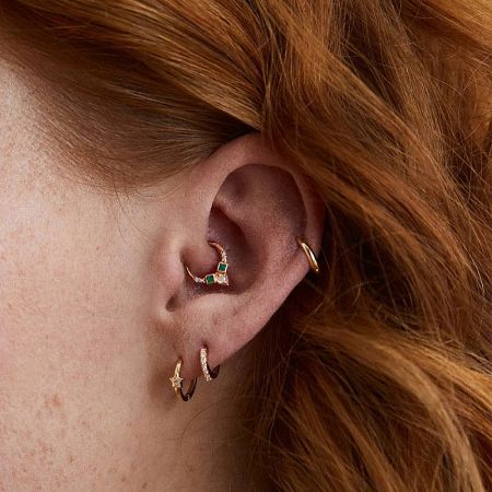 A close-up view of the 925 silver cartilage earring with green stones worn by a model.