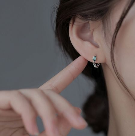 Close-up view of the 925 sterling silver mint cube stud earring worn on an ear, showcasing its aqua crystal.