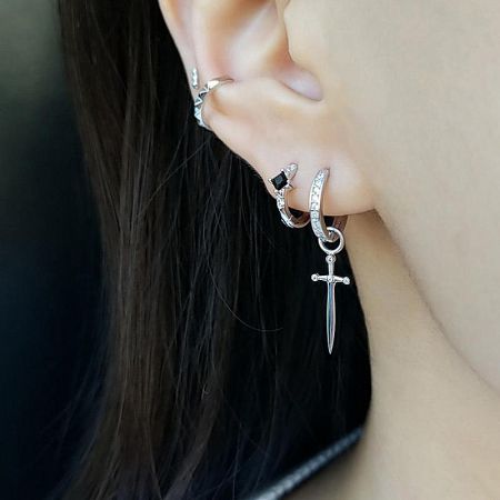 A stylish ear curation featuring the dagger pendant earring among other studs and hoops.