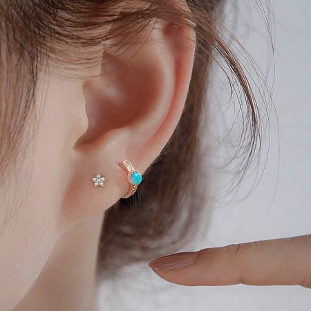 Close-up of a woman's ear wearing the 7mm sterling silver opal hoop earring, showcasing its size and fit.
