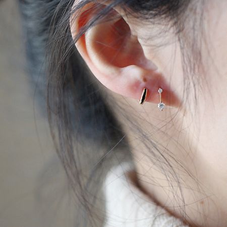 A model wears the tiny zircon huggie hoop earrings, demonstrating their elegant fit and scale.