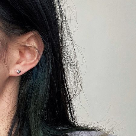 Model wearing the minimalist tiny heart stud earring to show scale and style.