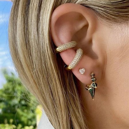 Close-up of a sterling silver ear cuff set featuring a diamond hoop and a green dagger-shaped earring.