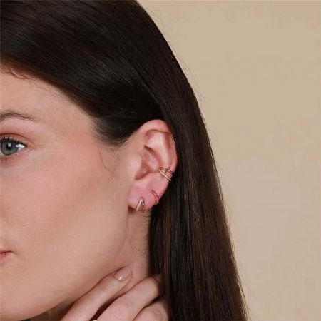 A stylish arrangement of multiple gold earrings on a model's ear, demonstrating versatility.