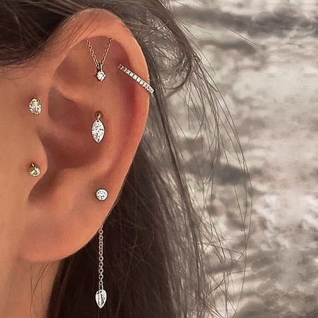 Model wearing multiple gold tassel chain stud earrings to showcase a layered helix look.