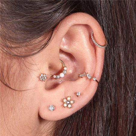 Model showcasing the tiny opal hoop earrings on the ear, paired with other studs for a stylish, layered look.