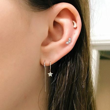 A model showcasing how the star hoop earrings can be styled with other piercings for a trendy look.
