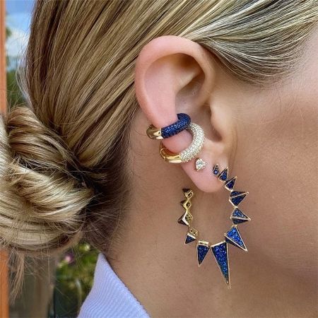 Model showcasing a layered look with a sterling silver ear cuff featuring blue triangle accents.