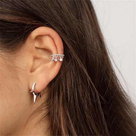 A model showcasing how the silver rivet hoop earrings can be styled.