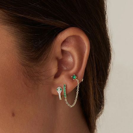 A model's ear showcasing a stylish arrangement of the 925 sterling silver chained huggie hoop and CZ stud earrings.