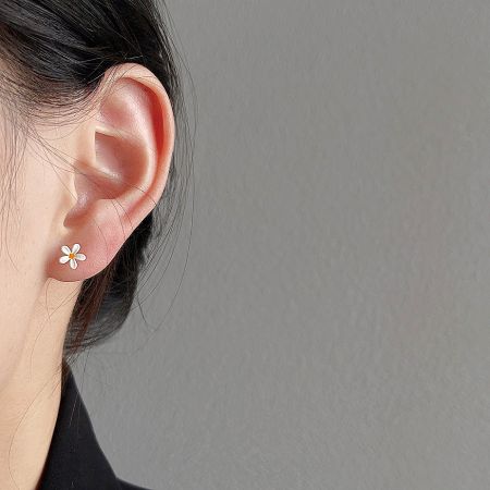 A close-up view of the mini enamel daisy flower stud earring being worn, showcasing its delicate size and appearance.