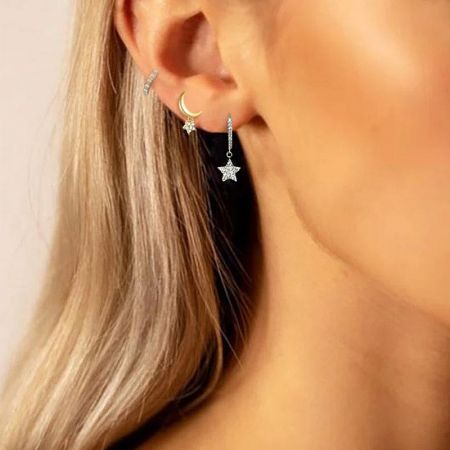A close-up of the earrings worn on a model, illustrating their delicate size and shine.