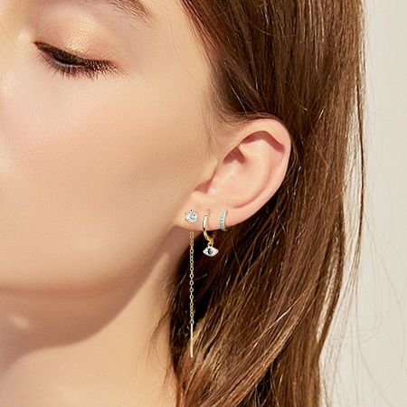 Model wearing a combination of earrings including the evil eye hoop for a stylish look.