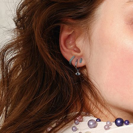 A lifestyle shot showing the evil eye earrings paired with a pearl necklace for an elegant ensemble.