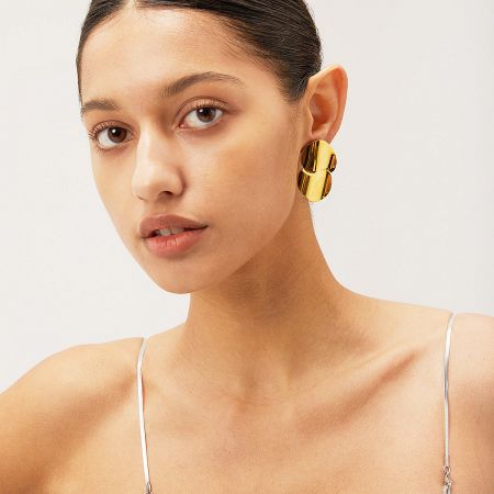 A model showcasing the gold geometric drop earrings, highlighting their scale and style.
