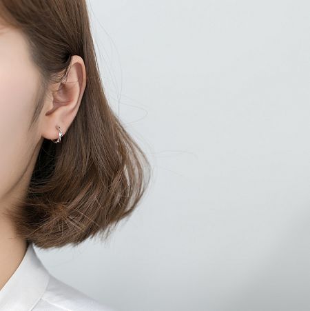 Model showcasing the elegant 925 Sterling Silver Wave Hoop Earrings to display how they look when worn.