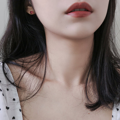 A portrait of a woman highlighting the red heart earring.