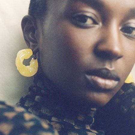 Close-up of a model wearing the amber yellow ruffle resin earrings.