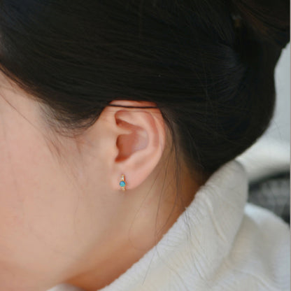 A detailed lifestyle shot of the 7mm opal and zircon hoop earring being worn.
