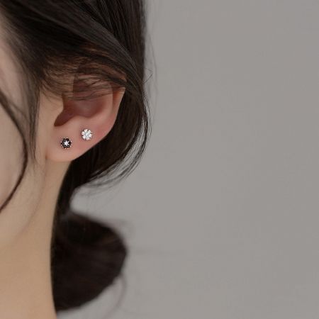 A close-up of a woman wearing the delicate flower stud earrings, showcasing their scale and sparkle.