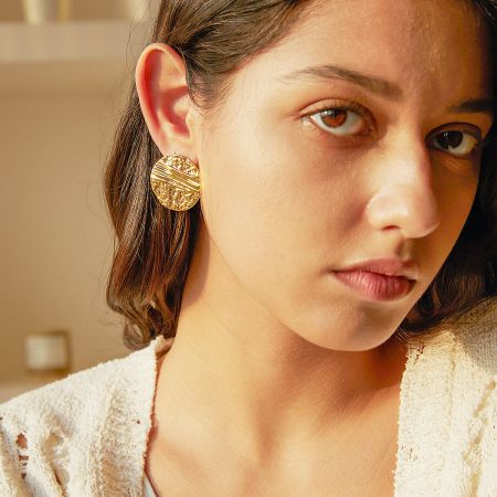 Side profile of a model wearing the gold round disc stud earrings, highlighting their elegant look.