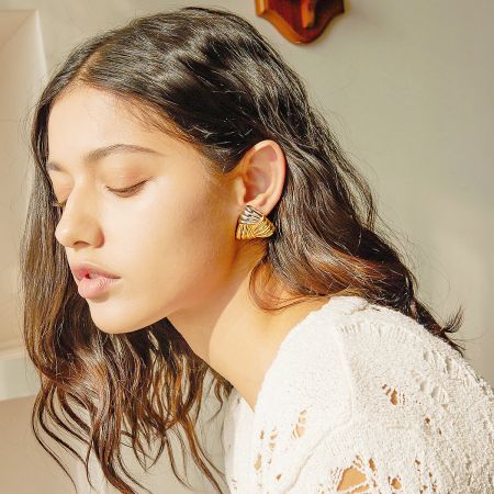 Close-up of a model wearing the gold triangle earrings, emphasizing their size and fashionable look.