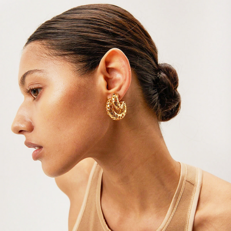 Profile view of a model wearing the chunky gold C-shaped hollow stud earrings.