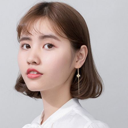 Model showcasing the elegant drop of the Gold Four Leaf Clover Dangle Chain Earrings.