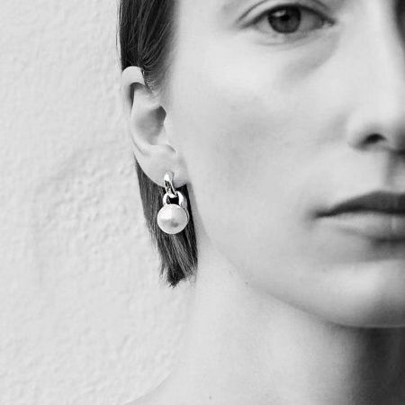 Lifestyle shot of a woman wearing a beautiful dangling pearl earring.