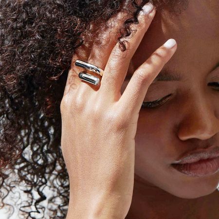 A close-up shot of a model's hand wearing the silver version of the ring set.