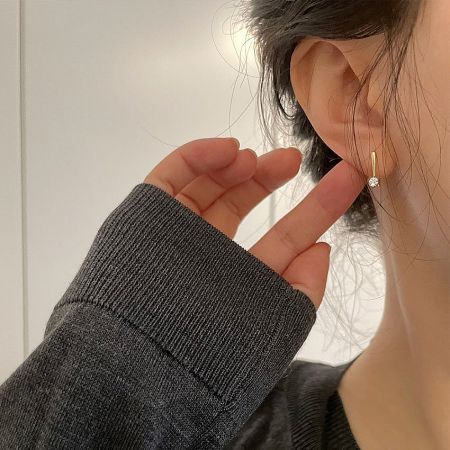 Side profile of a woman wearing the minimalist 14K gold plated sterling silver hook earring.