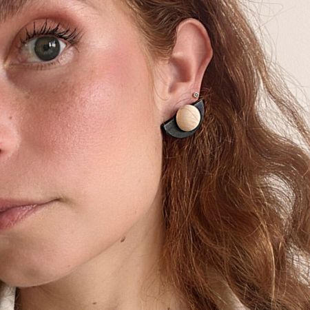 Lifestyle image showing a model wearing the unique black and wood fan-shaped earring.